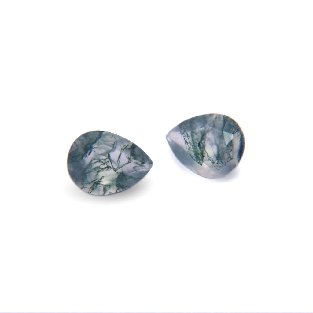Two pear cut moss agate stones on white, one turned to show the faceted crown