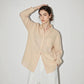 Side view of a woman in a lightweight linen blend button-up shirt with long sleeves and drop hem