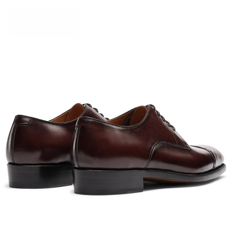 Rear view of a pair of brown cowhide derby shoes, stitched heel counters and low stacked block heels
