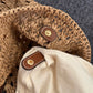 Hand holding the straw tote to show its large size and woven shoulder straps