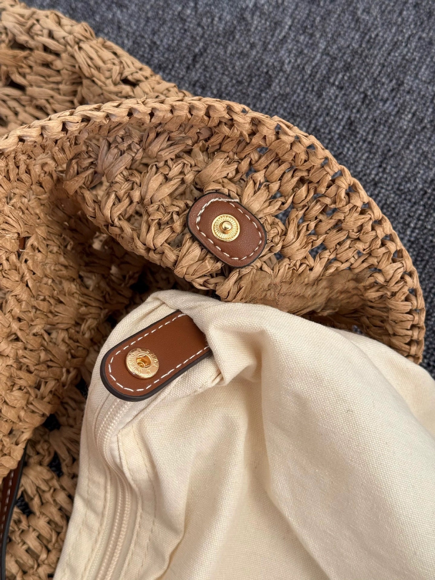 Hand holding the straw tote to show its large size and woven shoulder straps