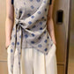 Close-up of the twist-knot waist tie and asymmetric hem on the diamond print blouse