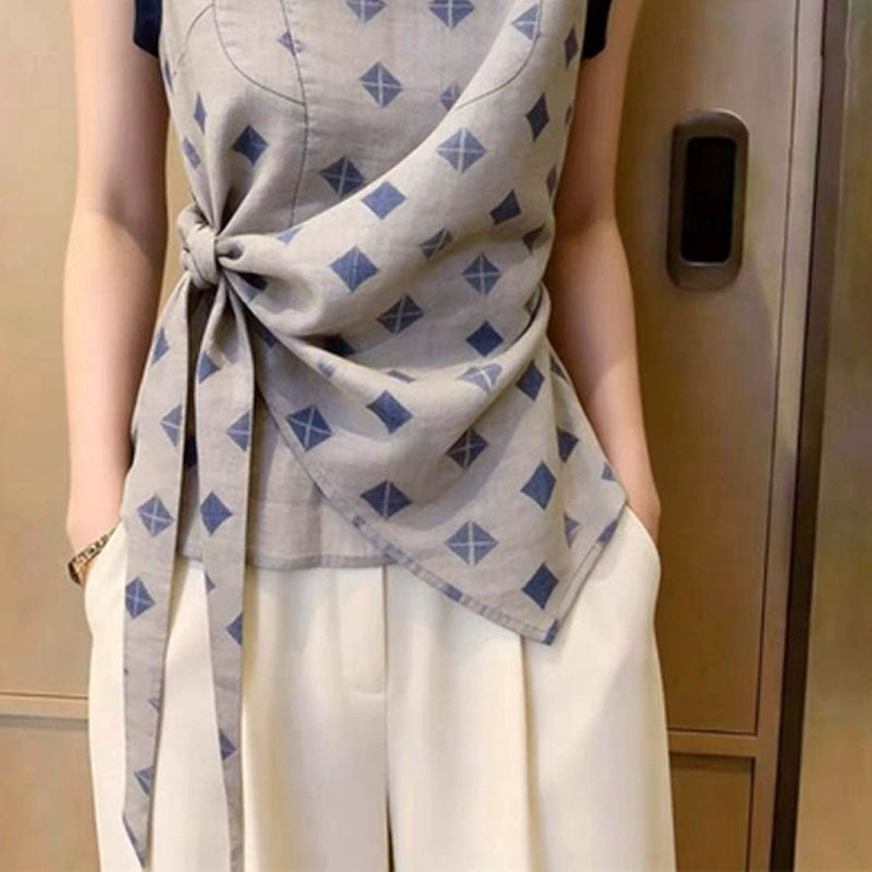Close-up of the twist-knot waist tie and asymmetric hem on the diamond print blouse