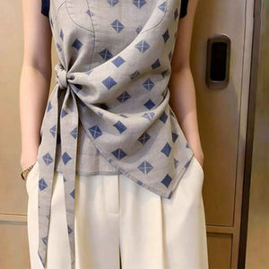Close-up of the twist-knot waist tie and asymmetric hem on the diamond print blouse
