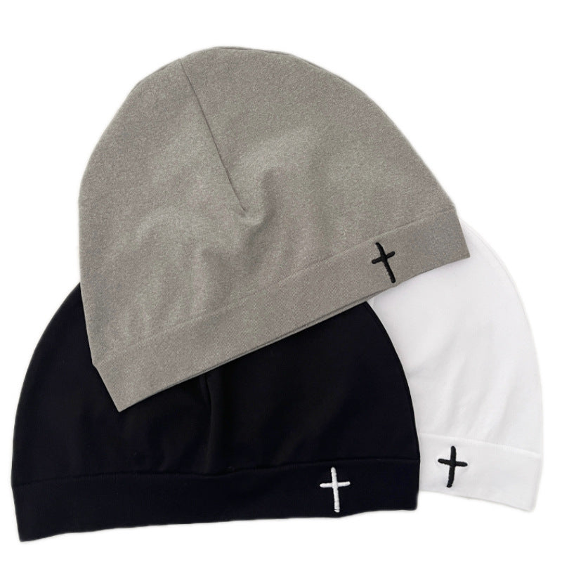 Knitted dome beanie with a small embroidered cross on the folded front cuff, no brim