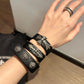Black leather concho cuff bracelet styled with a casual outfit on the wrist