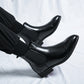 Side view of black Chelsea ankle boots with pointed cap toe, elastic gusset and low block heel on white fabric
