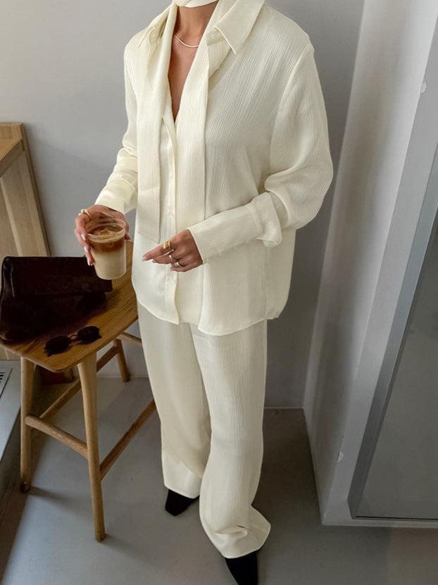 Close view of the buttercream crinkle shirt and wide leg trousers set with a slim self tie at the neck