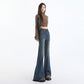 Walking shot of flared denim trousers brushing the top of brown boots