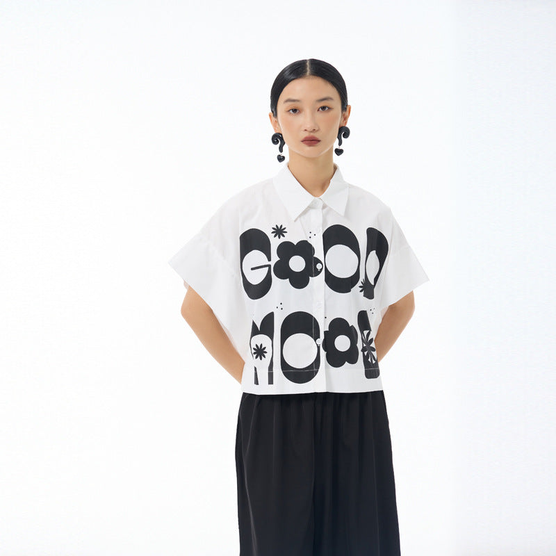 White cropped shirt with black Good Mood letters and daisy motifs, pointed collar