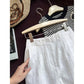 White linen shorts styled flat with knit top straw bag and summer book