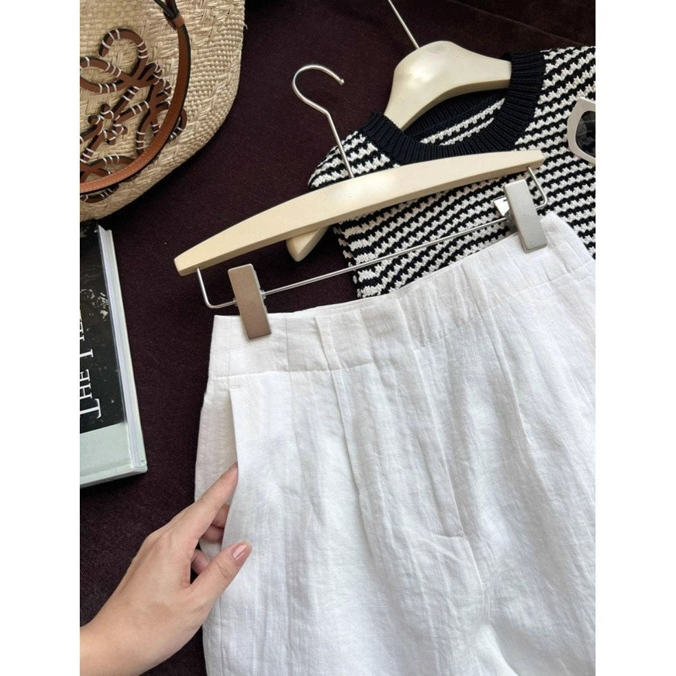 White linen shorts styled flat with knit top straw bag and summer book