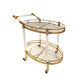 Two tier gold serving cart holding bottles and glasses styled as a drinks station