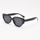 Black oval cat eye frame with grey tinted polarized lenses at an angle