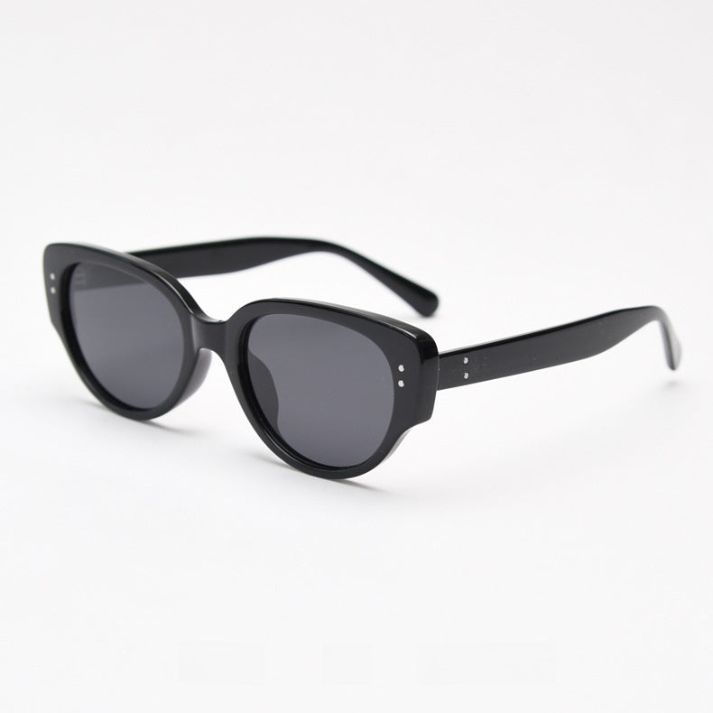 Black oval cat eye frame with grey tinted polarized lenses at an angle