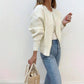Side view of the cream faux pearl trimmed knit cardigan worn open over jeans