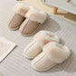 Beige and cream plush cuff mule slippers on a striped rug, each with a wide plush cuff