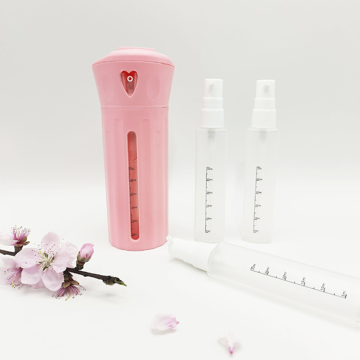Pink rotating four compartment travel bottle case beside four clear refillable spray bottles