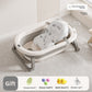 Baby bathtub with a white printed floating bath mat lying in the basin and a bath gift pack below