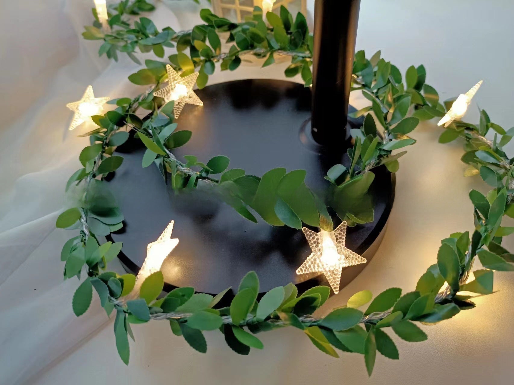 Star LED fairy string light on a green leaf vine with a warm glow, decorative photo