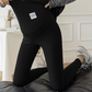 Black option photo of black maternity leggings with belly panel and label, woman kneeling on a sofa, size XXL