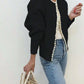 Black open front knit cardigan with faux pearl beads along the neckline and front edge