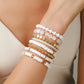 White colorway beaded bracelet stack worn layered up the wrist with gold-tone accents