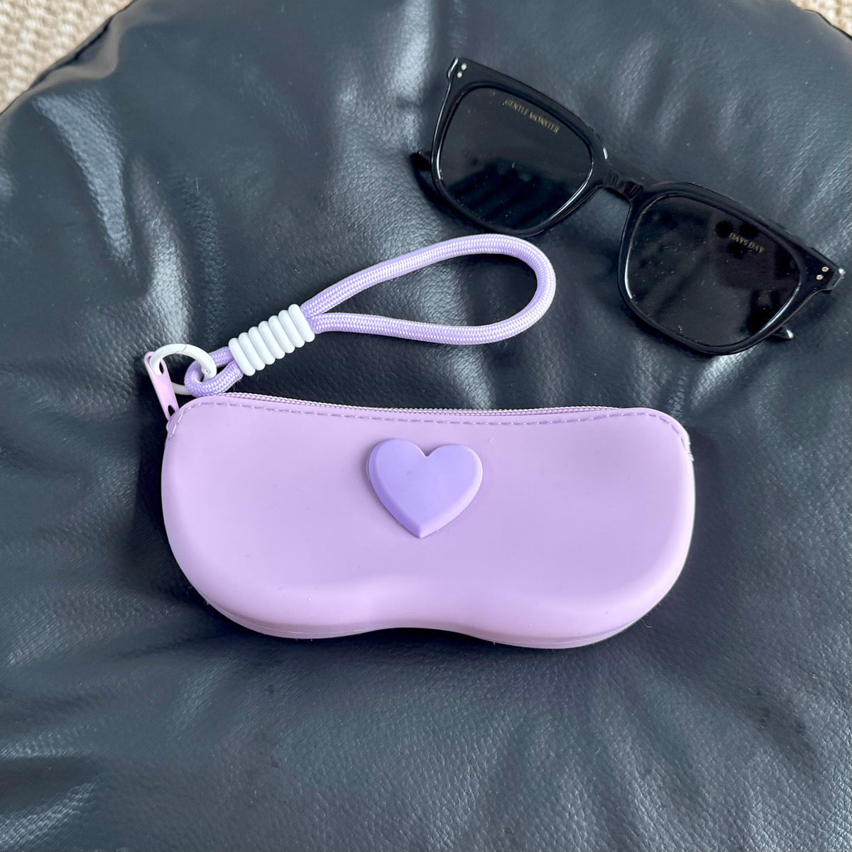 Purple silicone sunglasses case with a raised heart on the lid and a lilac wrist lanyard