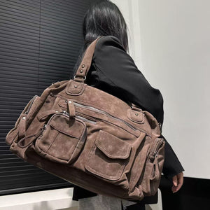 Woman carrying a large mocha brown PU shoulder bag over one shoulder by its twin handles, seen from behind