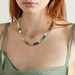 Woman wearing the jewel multicolor natural stone beaded necklace with freshwater pearls and glass daisy accents
