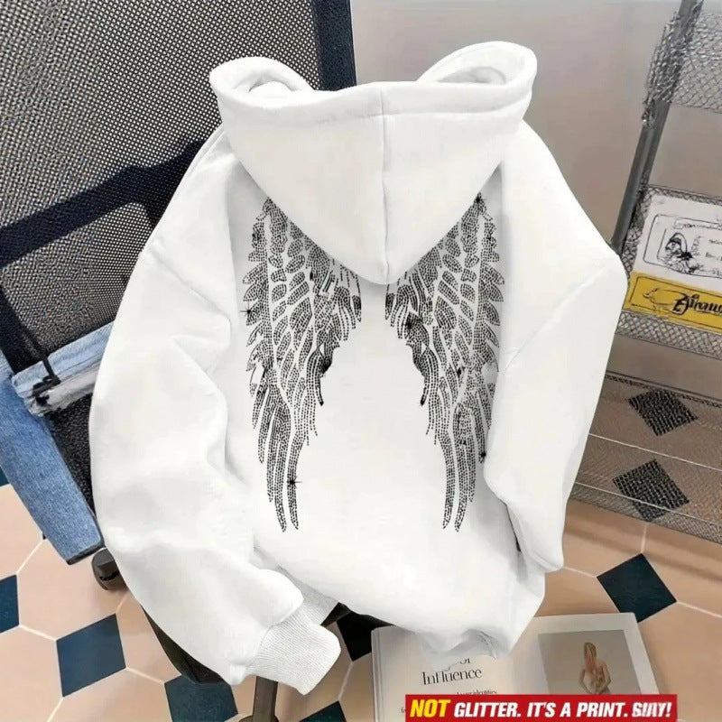 White hoodie back with silver rhinestone wings on a chair, shown with a stone close-up