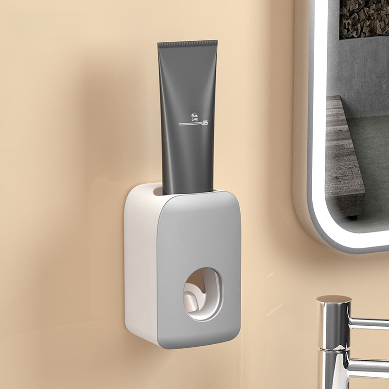 Fashionable black QNEST toothpaste dispenser on the wall with a full tube standing upright in the top socket