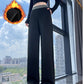 Woman in black high-waisted wide-leg pants with a gray waistband by a window, fleece lining graphic above