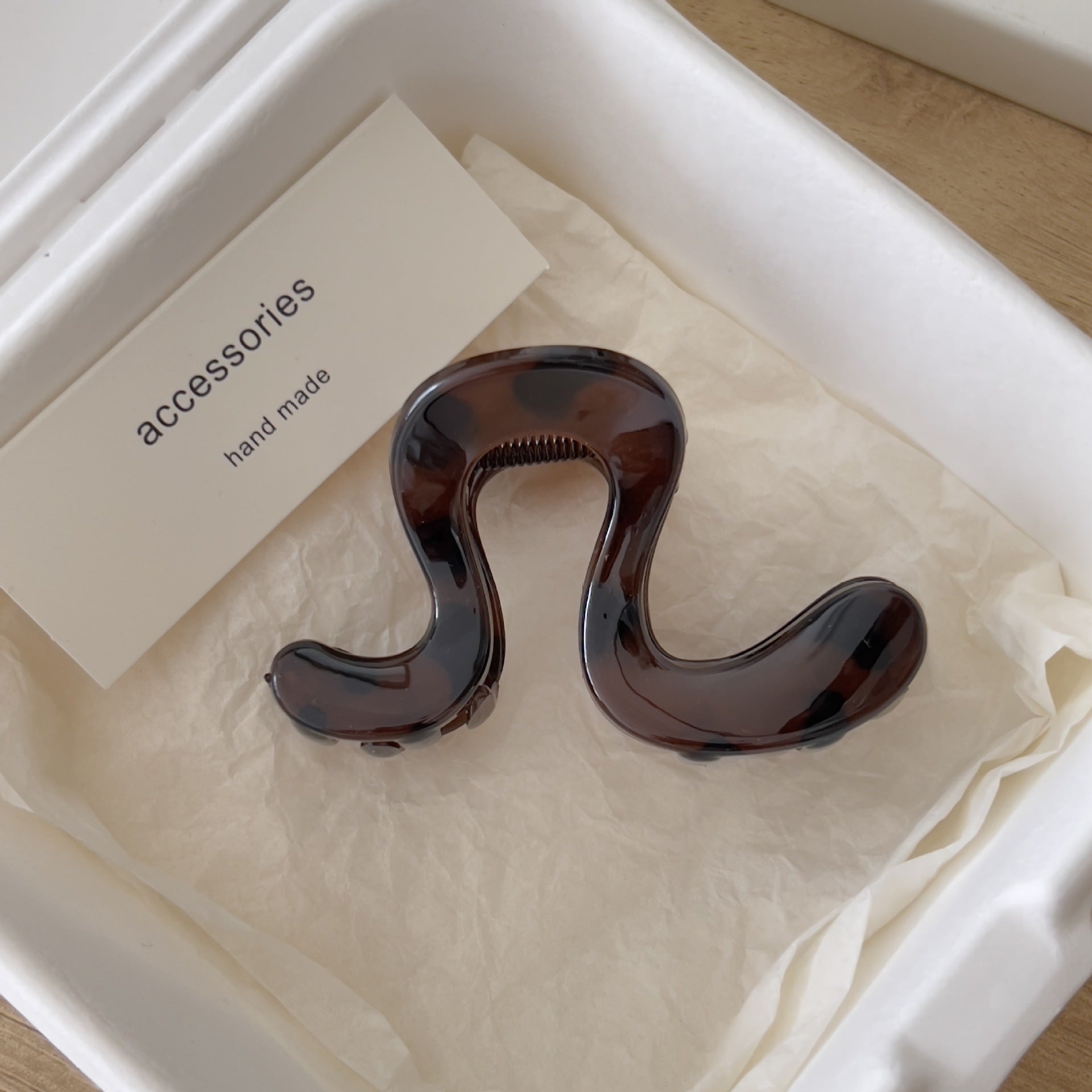 Large wavy acrylic hair claw clip shown from the side in a cream gift box