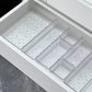Clear acrylic drawer organizer trays sorting makeup and small bottles in a drawer
