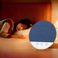 Blue sleep speaker on a nightstand with a sleeper resting in warm lamplight