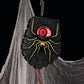 Black spiderweb spider Halloween doorbell with a glowing red eyeball hanging from a loop on cobwebs
