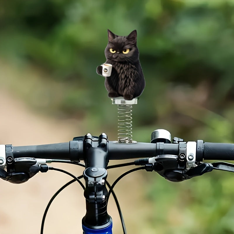 Black cat coffee mug spring ornament bobbing on a bicycle handlebar against a green outdoor blur