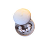 Beige sleep earbuds shown next to a phone for Bluetooth pairing