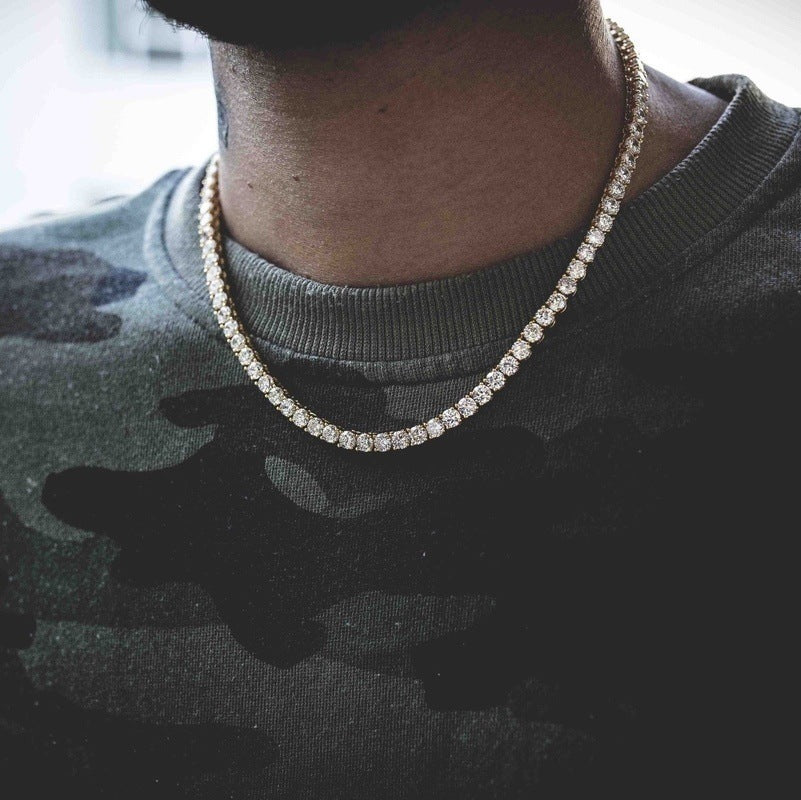 Man wearing a single row stone tennis chain necklace over a dark camouflage t-shirt