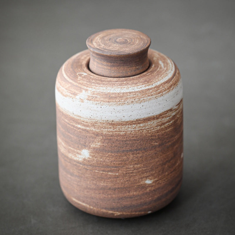 Three ceramic storage jars grouped on an open kitchen shelf