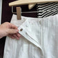 White linen shorts front zip fly open showing button and high waistband