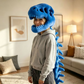 Blue plush dinosaur skeleton head mask worn from the side, jaws open around the face