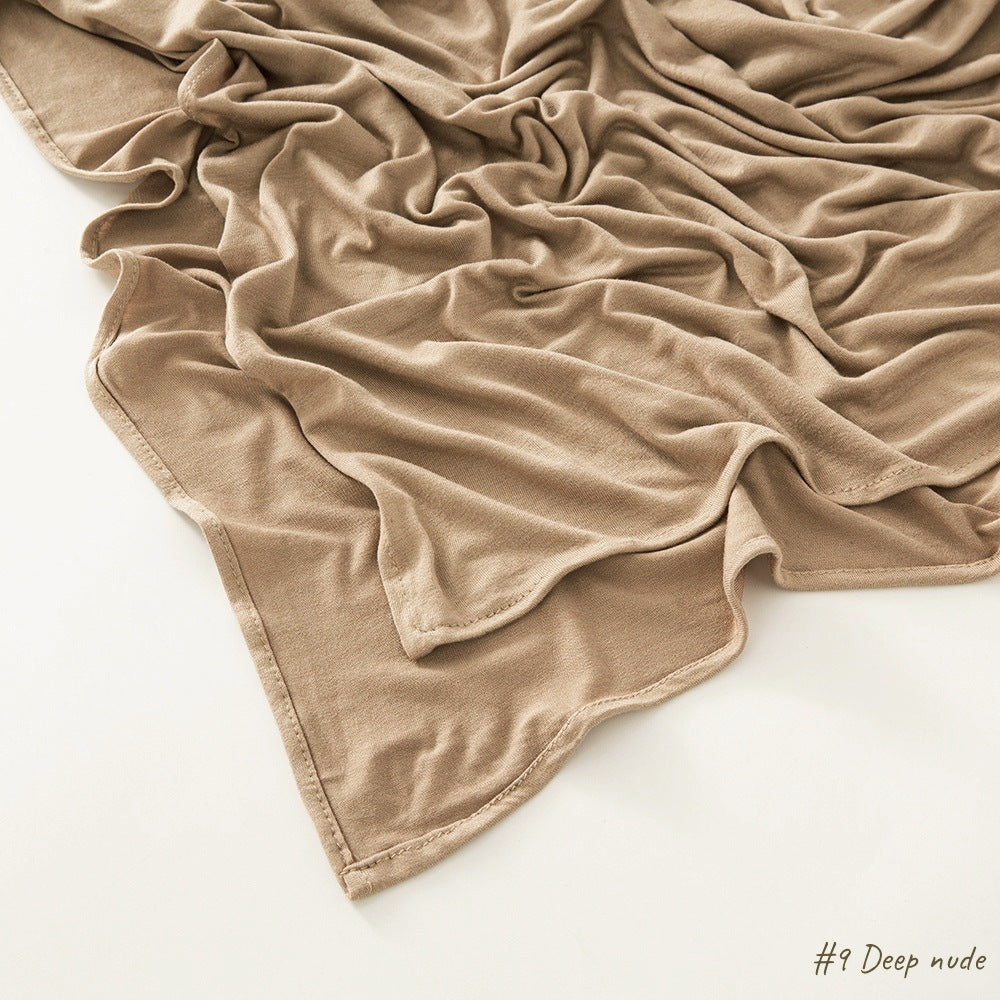 Corner of the modal cotton headscarf wrap showing the neat rolled hem and flat solid color
