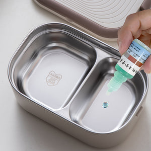 Brown electric heated lunch box beside its gift box with the black power cord and US plug