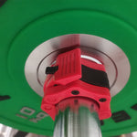 Red quick release barbell collar clamped onto a steel barbell sleeve beside a green weight plate