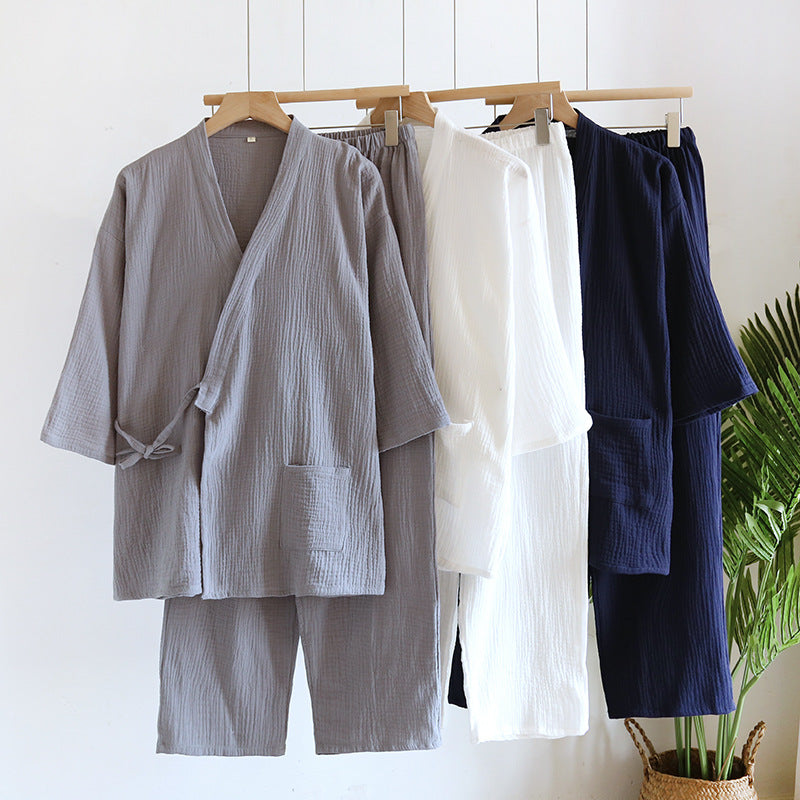 Gray, white and navy kimono style cotton gauze pajama sets hanging on wooden hangers beside a green plant