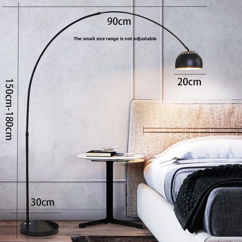 Gold arc floor lamp lighting a reading corner over an armchair at night