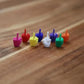 Eight mini middle finger figures lined up in pink, red, yellow, blue, purple, green, white and orange