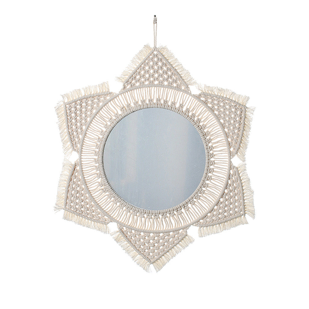 Boho wall mirror hung above a console reflecting daylight in the room